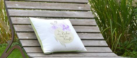A wooden bench with a cushion featuring floral designs and text.