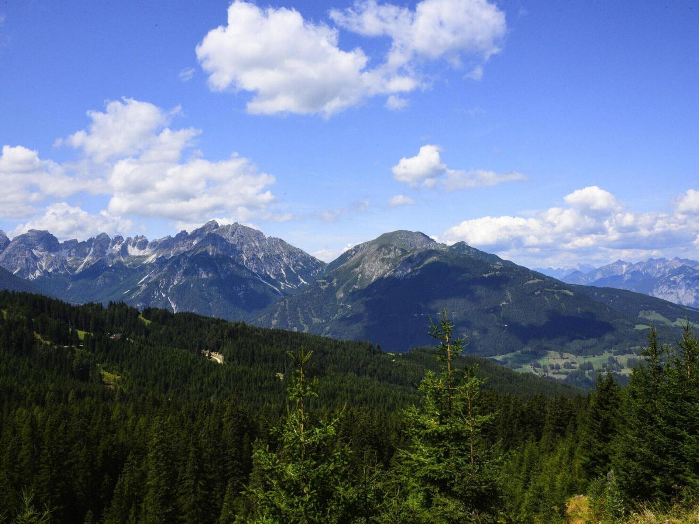 A mountainous landscape with dense forests and a clear sky.