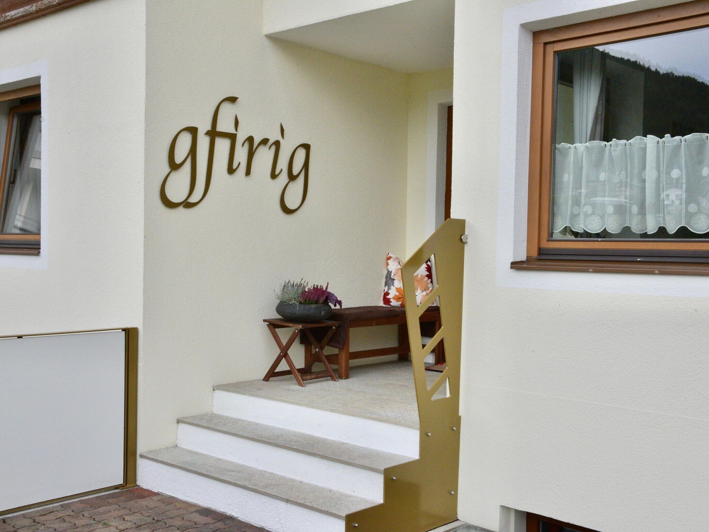 A staircase leading to a porch with a sign reading "gfiria" and a small table with a plant.