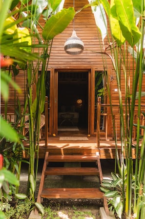 A wooden house with a porch, surrounded by lush greenery. - Lumeria Yoga (Ubud)