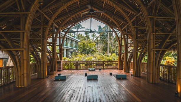 A spacious bamboo structure with a high ceiling and a view of tropical greenery. - Lumeria Yoga (Ubud)