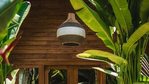 A wooden cabin with a glass door, surrounded by lush tropical plants. - Lumeria Yoga (Ubud)