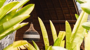 A wooden structure with a curved roof, surrounded by lush green foliage. - Lumeria Yoga (Ubud)