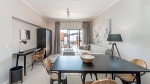 Ein modernes Wohnzimmer mit Essbereich, einer Couch, einem Fernseher und einer Lampe.