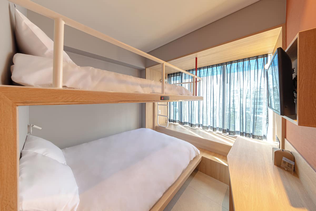 A bunk bed room with a desk and a TV.