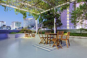 An outdoor seating area with a table and chairs, surrounded by greenery and overlooking a cityscape. - Uhoostay (Seoul)
