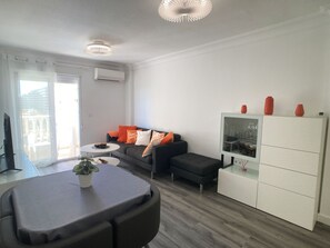 Una sala de estar moderna con un sofá, una mesa de centro y un aparador con objetos decorativos.