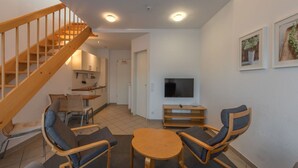 Una sala de estar moderna con una escalera de madera, un comedor y un televisor.