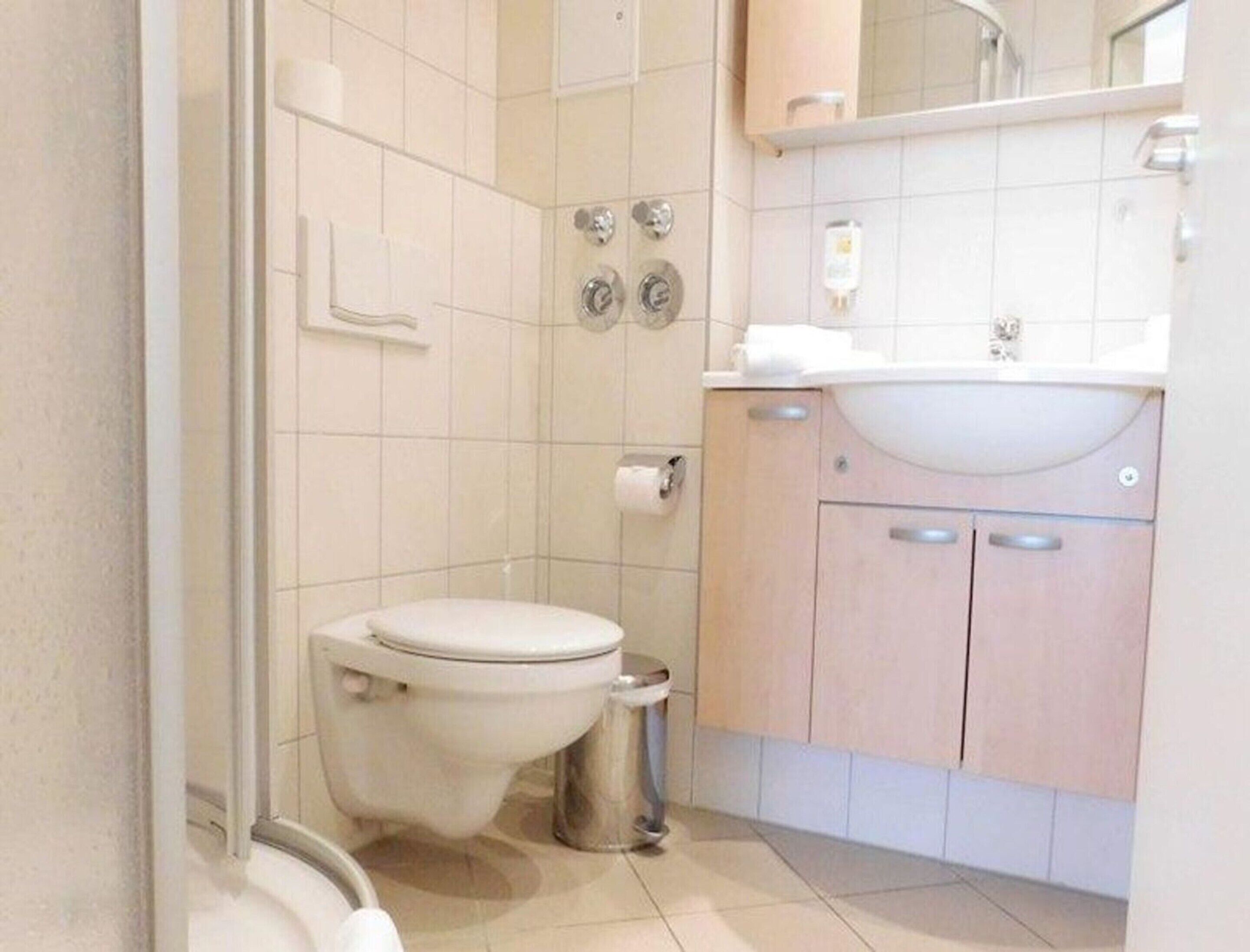 A bathroom with a toilet, a sink, and a shower area.