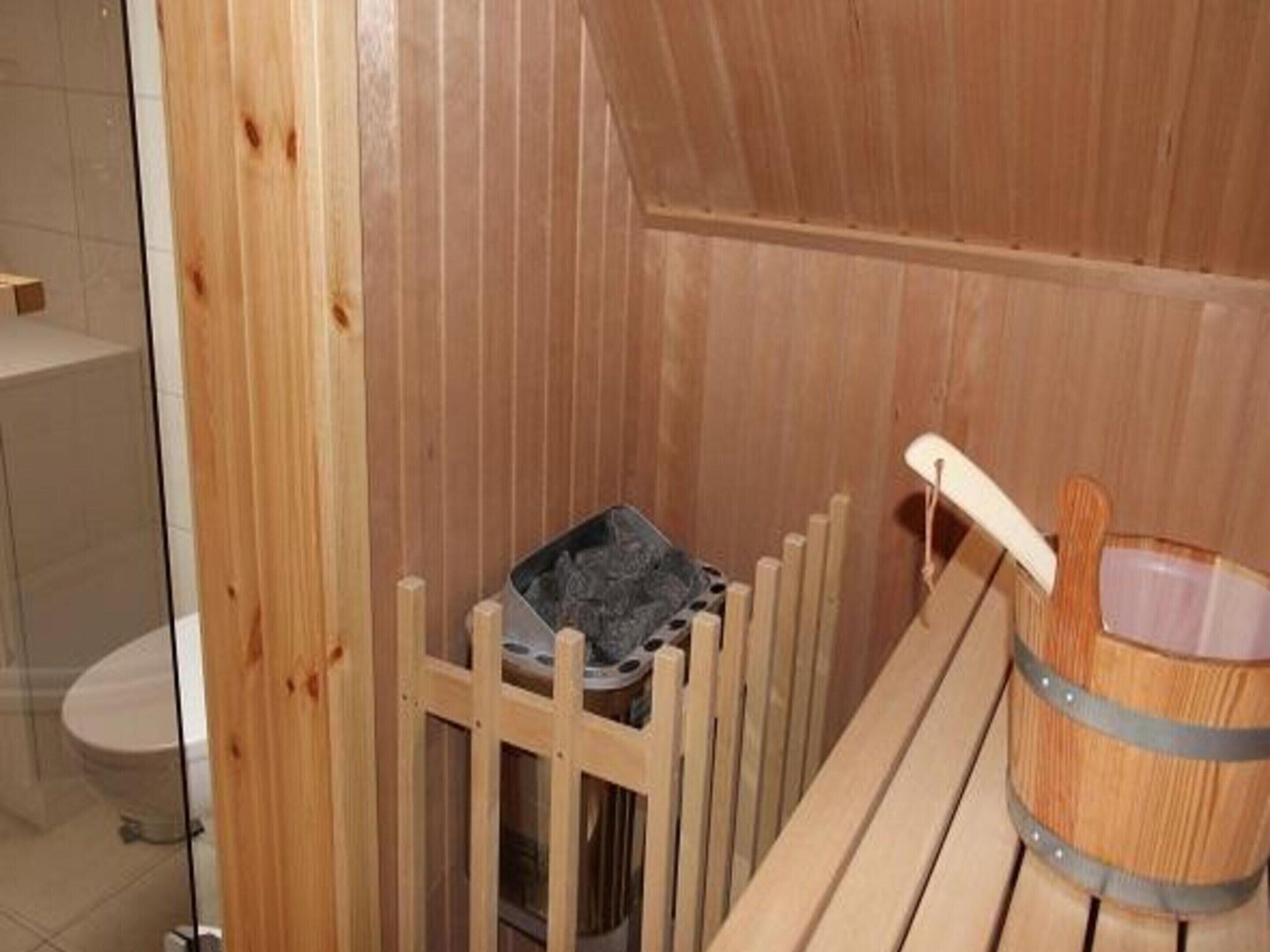 A wooden sauna with a bench and a bucket.