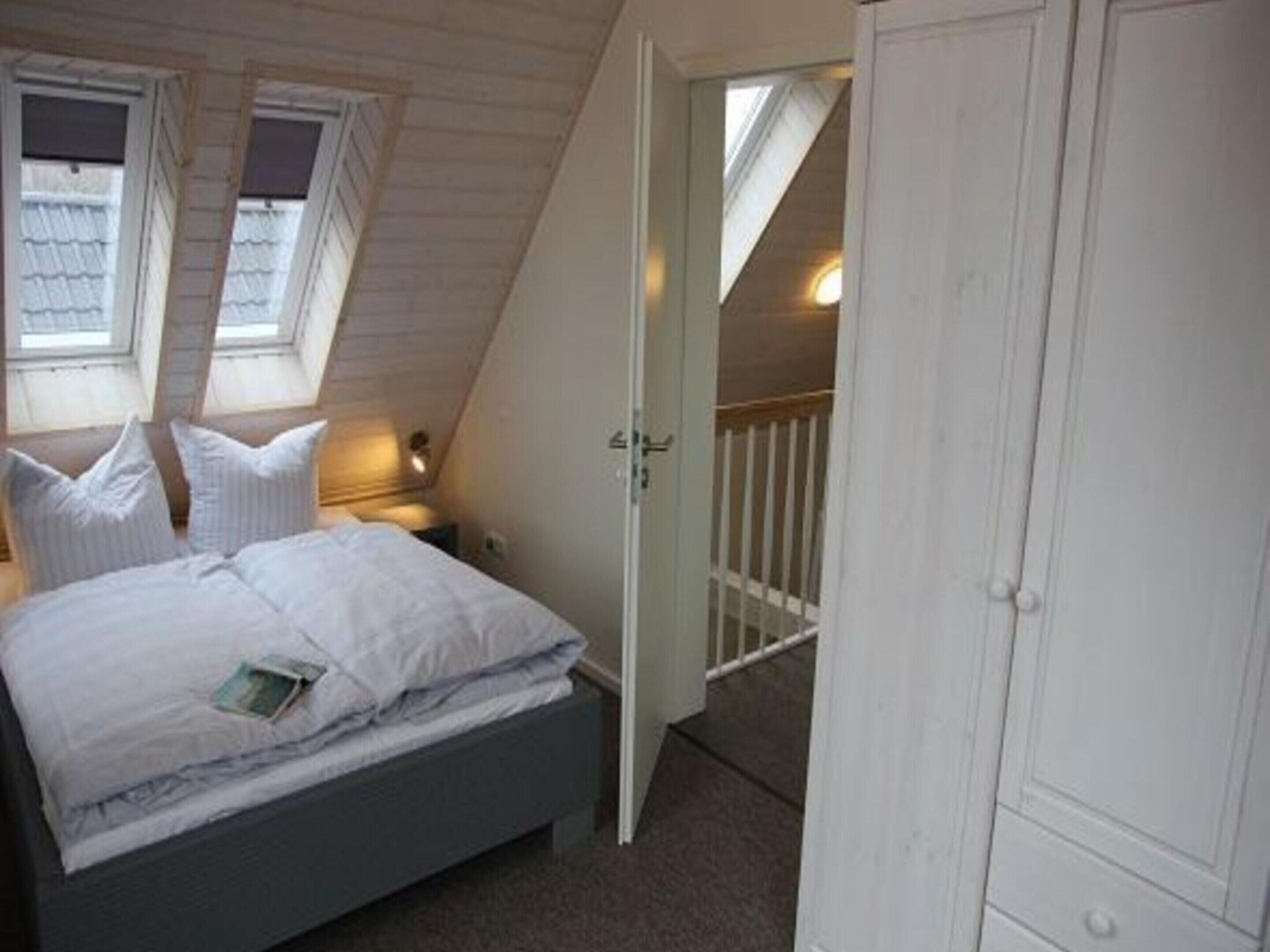 Un dormitorio con cama, armario y ventana con vistas al exterior.