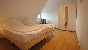 Un dormitorio con una cama, una silla y un armario.