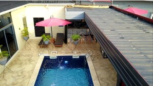 A rooftop pool with a view of the surrounding area, including lounge chairs and umbrellas. - Daltons Hotels and Resort (Abuja)