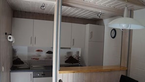 Eine kleine Küche mit weißen Schränken, einer Holz Arbeitsplatte und einem Essbereich mit Tisch und Stühlen.