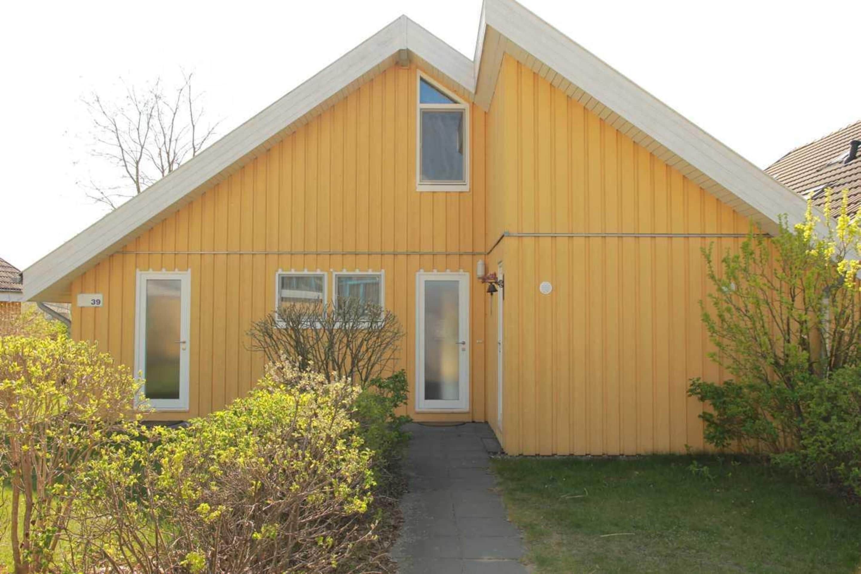 Un bâtiment jaune avec un toit à pignon, un petit porche et le chiffre « 39 » peint sur le côté.