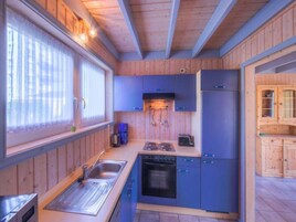 A compact kitchen with wooden walls, a sink, a stove, and cabinets.