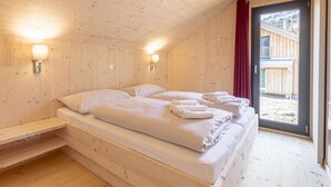A wooden cabin room with two beds, a window, and a door leading outside. - Attractive Chalet With Terrace (Sankt Georgen am Kreischberg)