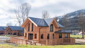 A wooden cabin with a sloped roof, a fenced yard, and a mountainous backdrop. - Attractive Chalet With Terrace (Sankt Georgen am Kreischberg)