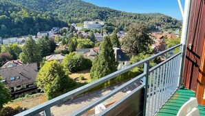 Un balcon donnant sur une ville entourée de collines.