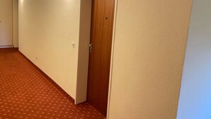 Un couloir avec une porte en bois et des luminaires fixés au mur.
