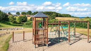 Ein Spielplatz mit einer hölzernen Kletterkonstruktion und einer kleinen Schutzhütte.