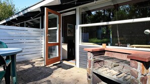 Eine Terrasse im Freien mit Grill, Tisch und Stuhl.
