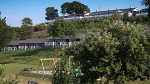 Ein Wohngebiet mit Häusern an einem Hang, ein Spielplatz mit Schaukeln und Picknicktischen.