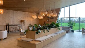 A modern interior with a wooden ceiling, large windows, and a central seating area with cushions. - The Brookside Escape (Antoing)