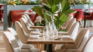 A dining area with a long table set for a meal, surrounded by upholstered chairs with red accents. - The Brookside Escape (Antoing)