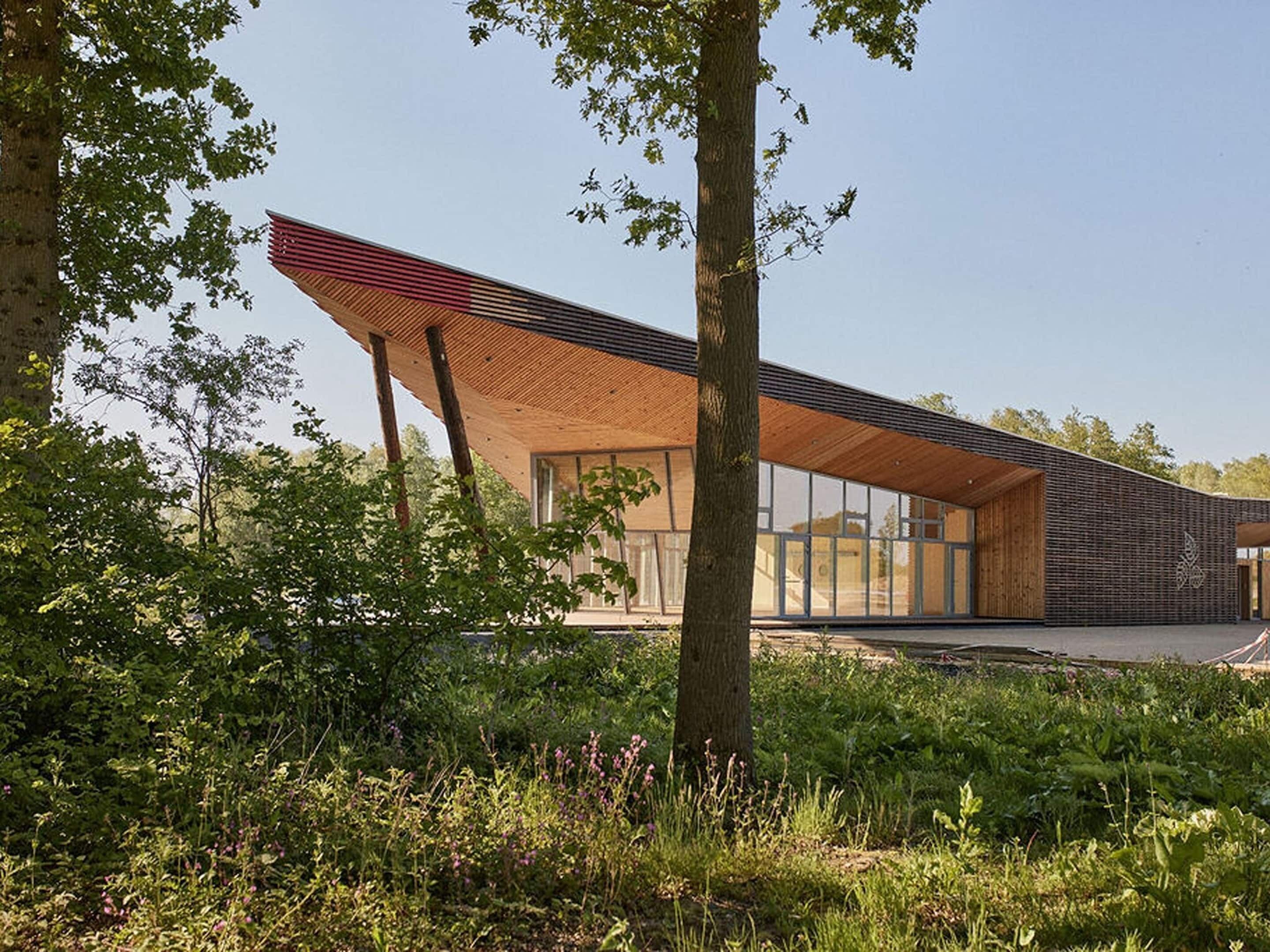 Ein modernes Gebäude mit geneigtem Dach, großen Fenstern und einer Holzfassade.