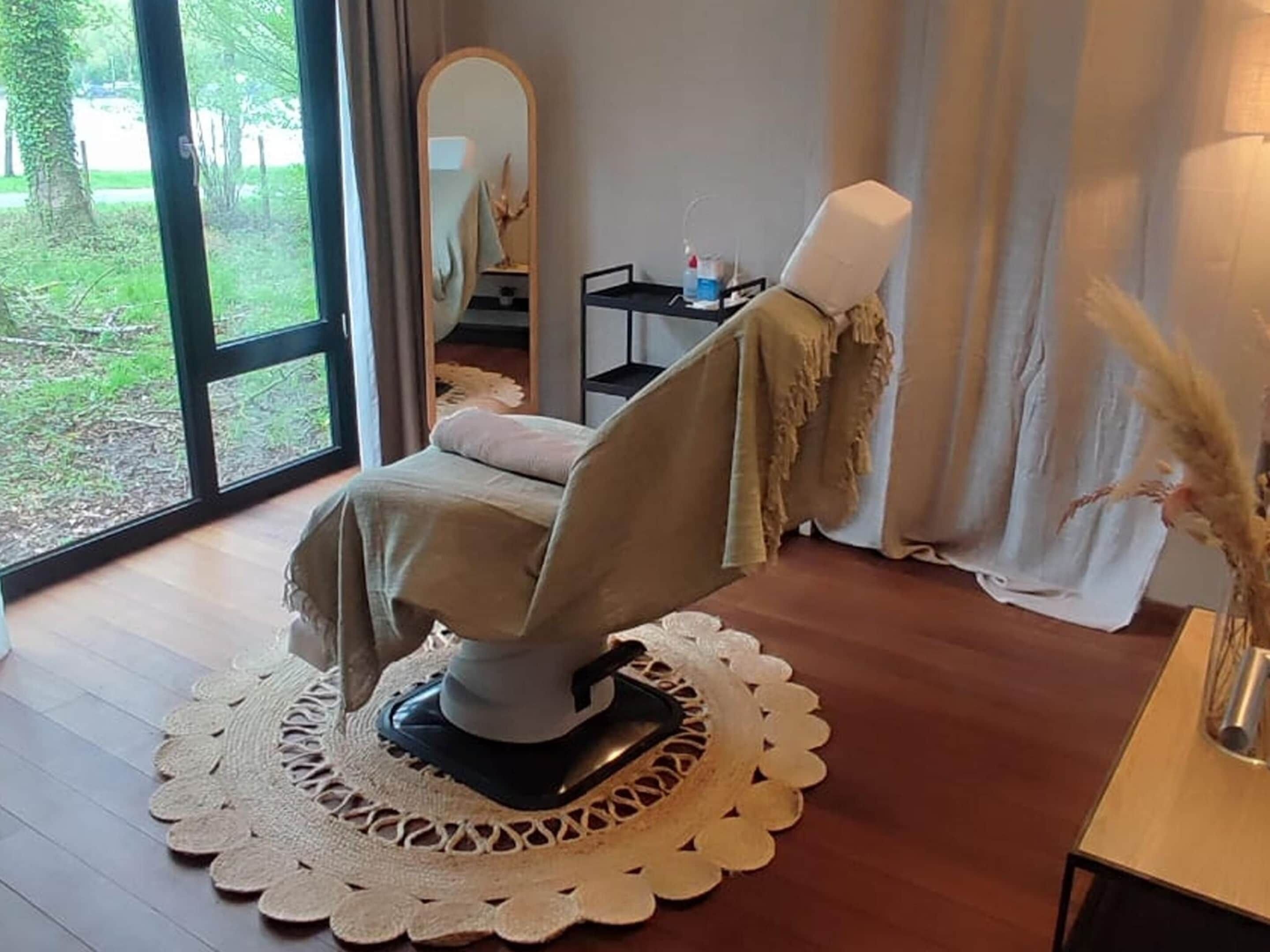 A room with a massage chair, a large mirror, and a view of greenery outside.