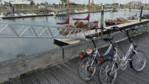 A wooden dock with bicycles parked, a marina with sailboats, and a building labeled "KYCN" in the background. - Cosy Apartment With Terrace Near Beach (Nieuwpoort)