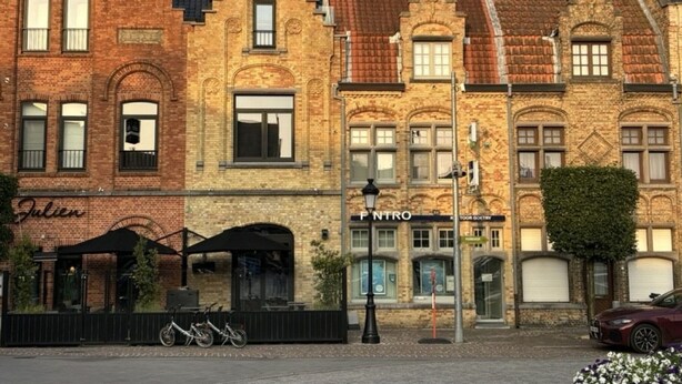 A row of historic brick buildings with a café named "Julien" and a bookstore called "FINTRO". - Cosy Apartment With Terrace Near Beach (Nieuwpoort)