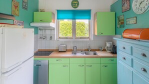 A kitchen with green cabinets, a white refrigerator, a sink, and a window with a view of greenery. - Nice Holiday Home Near Beach (Wemeldinge)