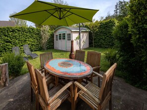 A round wooden table with six chairs and a green umbrella. - Nice Holiday Home Near Beach (Wemeldinge)