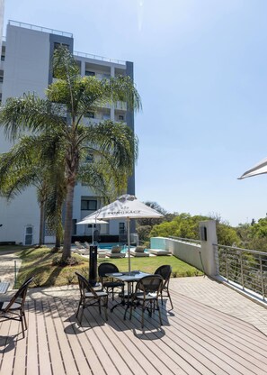 A rooftop patio with a pool, palm trees, and outdoor furniture. - Stylish & Elegant With Epic Views Near Menlyn (Pretoria)