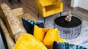 A living room with a yellow armchair, a patterned sofa, and a round coffee table with a decorative item on it. - Stylish & Elegant With Epic Views Near Menlyn (Pretoria)