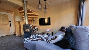 A cozy room with a sofa, a hanging chair, a fireplace, and a TV mounted on the wall. - Beautiful Chalet With Sauna (Sankt Georgen am Kreischberg)
