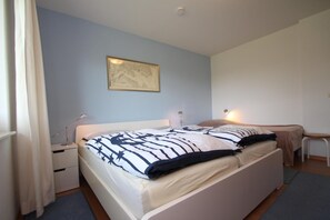 A bedroom with a bed, bedside table, lamp, and a framed picture on the wall.