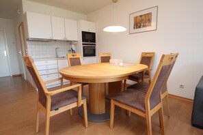 A modern kitchen with white cabinets, a central island, and a dining table with six chairs.