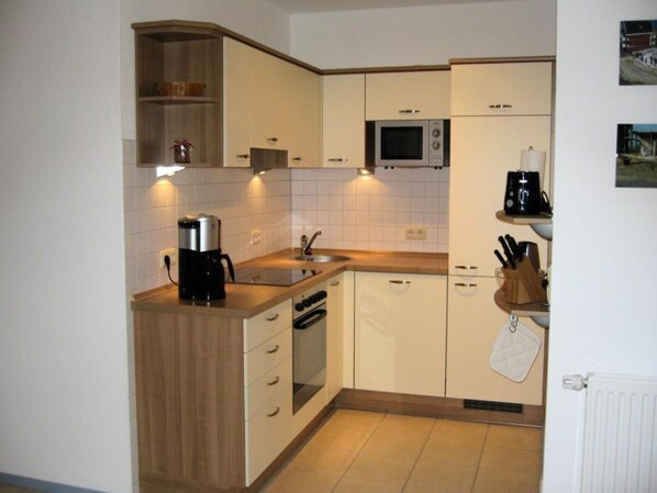 A compact kitchen with white cabinets, a microwave, a coffee maker, and a sink. - Liebevoll Eingerichtetes Appartement (Rechlin)