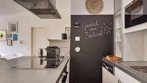 A modern kitchen with a blackboard displaying 'Gemert van Zeeland' and a decorative wall piece. - Holiday Home in Kamperland Near Beaches (Kamperland)