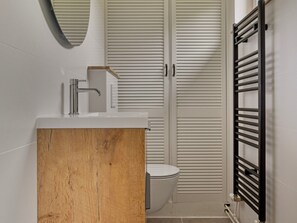A modern bathroom with a wooden vanity, a white toilet, and a black towel rack. - Holiday Home in Kamperland Near Beaches (Kamperland)
