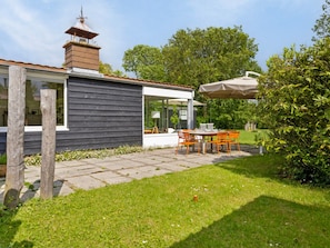 A modern house with a patio, outdoor seating, and a garden. - Holiday Home in Kamperland Near Beaches (Kamperland)