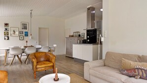 A modern living room with a sofa, a coffee table, and a dining area with chairs and a table. - Holiday Home in Kamperland Near Beaches (Kamperland)