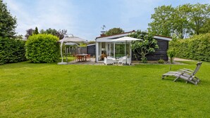 A backyard with a patio area, a covered seating area, and a wooden deck. - Holiday Home in Kamperland Near Beaches (Kamperland)