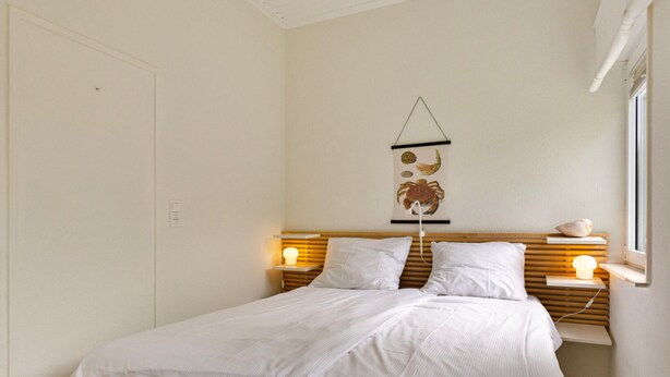 A neatly made bed with white linens, a wooden headboard, and bedside lamps. - Holiday Home in Kamperland Near Beaches (Kamperland)