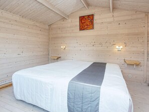 A wooden cabin bedroom with a bed, two wall-mounted lights, and a painting on the wall. - Charming Retreat by the Sea - By Traum Ferienwohnungen (Odder)