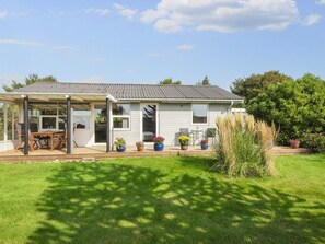 A single-story house with a covered patio, a front door, and a small garden area with potted plants. - Charming Retreat by the Sea - By Traum Ferienwohnungen (Odder)