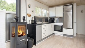 Une cuisine moderne dotée d’un poêle à bois, d’appareils électroménagers en acier inoxydable et de meubles blancs.